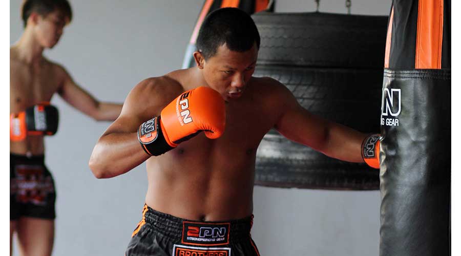 A thai figher training on the heavy bag. A great representation of choosing the best cheap boxing gloves for 2021.